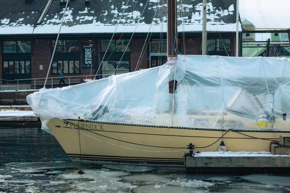 A marine battery being lifted out of a boat's battery compartment for winter storage