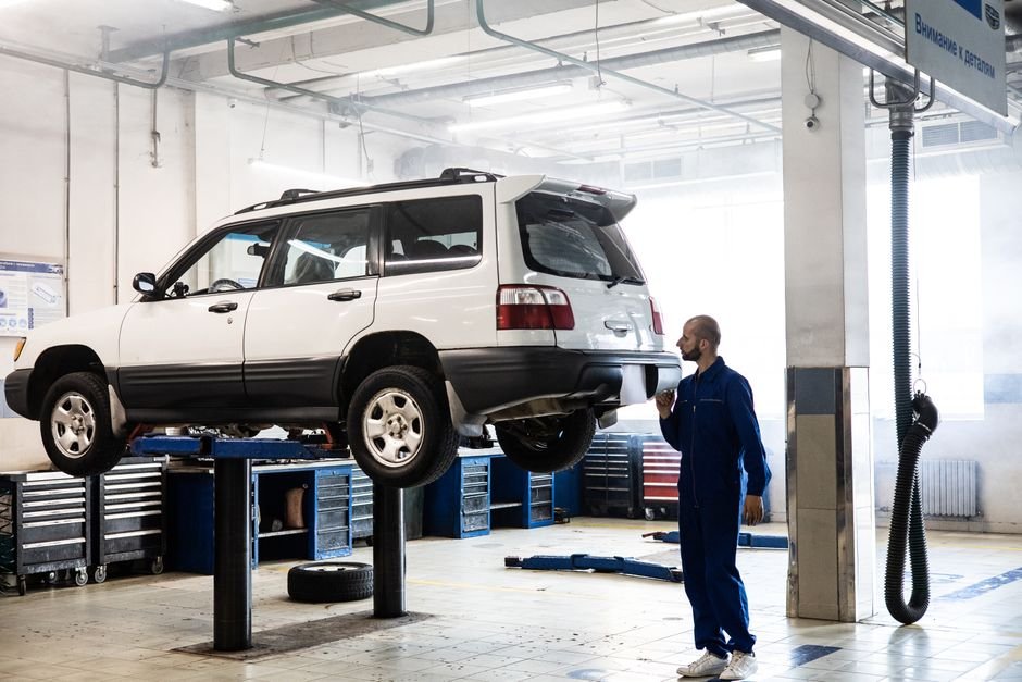 A car pulled into a bay at a state vehicle inspection station with a technician checking under the hood