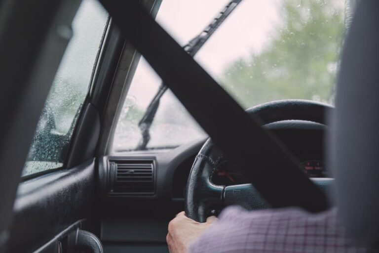 Close-up of a car's steering wheel turned slightly off-center while driving on a straight road