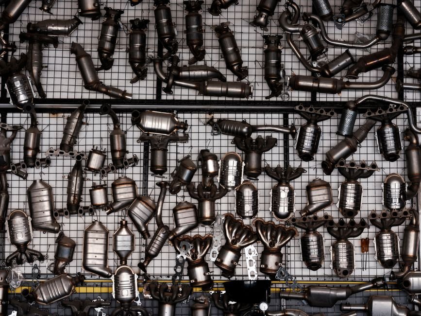 A catalytic converter and exhaust piping visible underneath a car on a lift