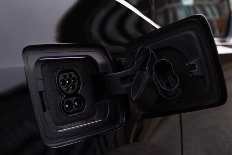 Close-up of an open charging port on an electric car showing the connector pins and charge door