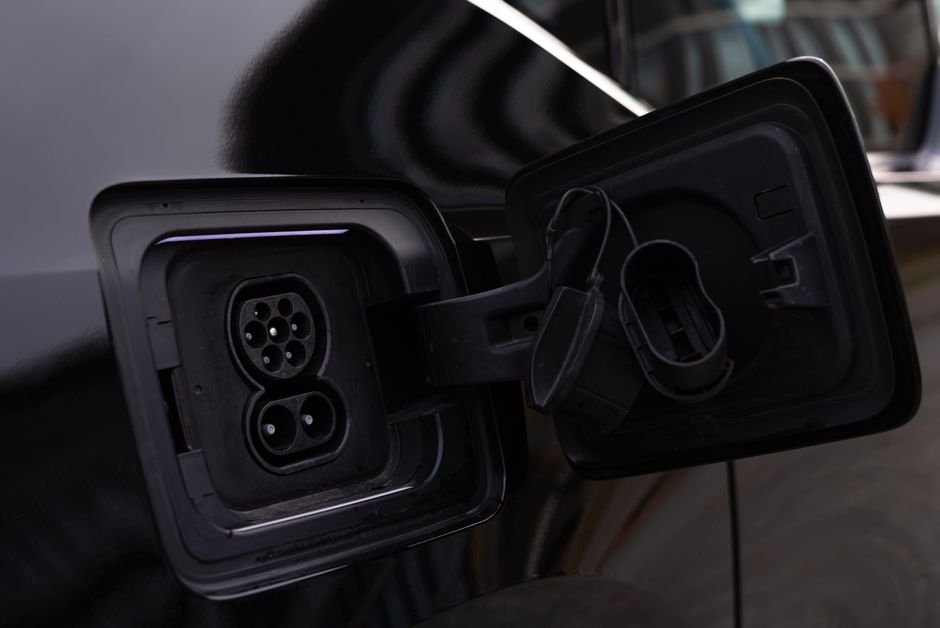 Close-up of an open charging port on an electric car showing the connector pins and charge door