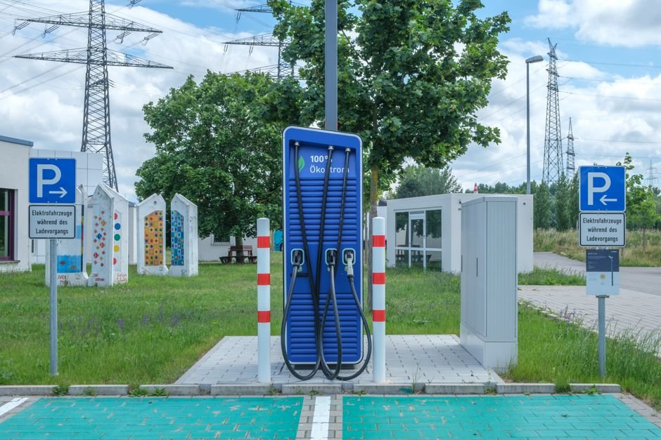 An electric car plugged in at a DC fast charging station along a highway