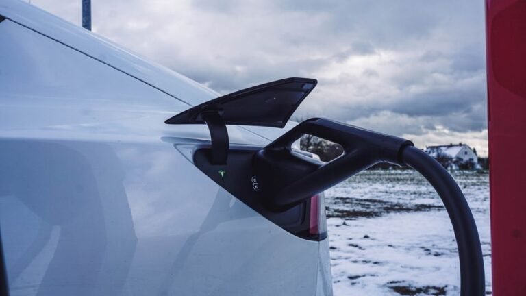 An electric car plugged into a charger in a snow-covered parking lot
