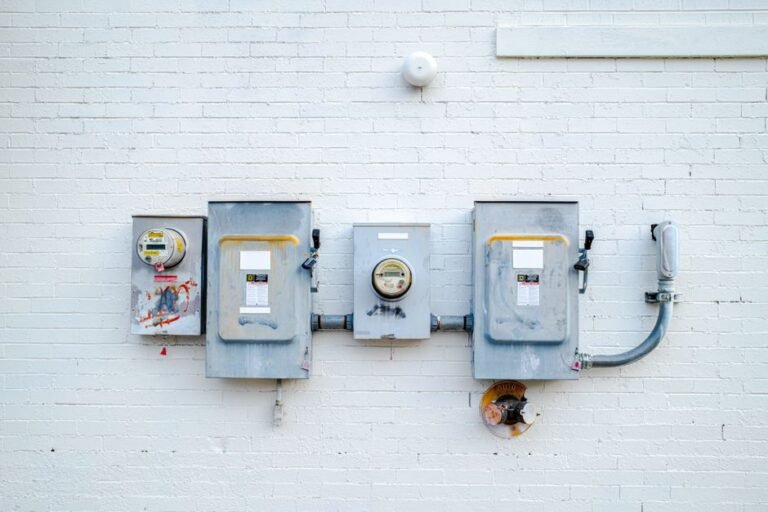 A digital electric utility meter mounted on the exterior wall of a house