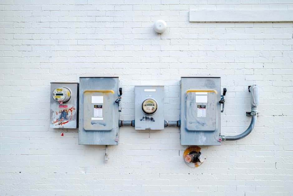 A digital electric utility meter mounted on the exterior wall of a house