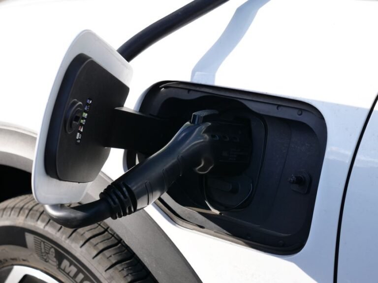 An electric car connected to a fast charging unit whose screen shows the elapsed charging time