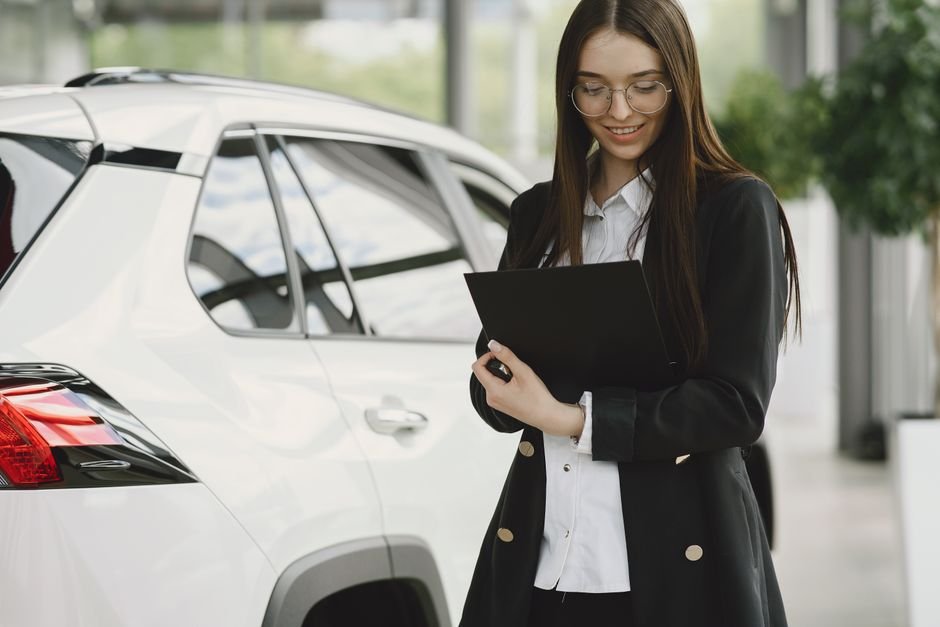 A warranty document on a clipboard next to a parked electric car
