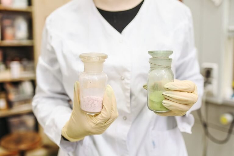 A researcher holding a thin sheet of graphene material with lab equipment in the background