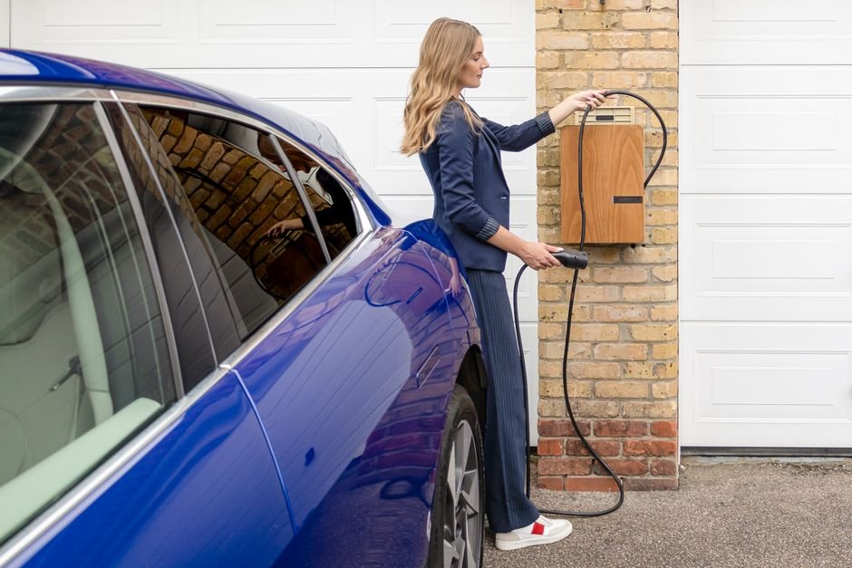 Two wall-mounted home EV chargers with coiled charging cables hanging on a garage wall