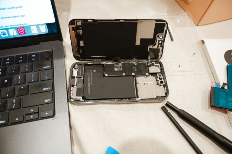 A rectangular laptop battery pack resting on a wooden desk next to an open laptop