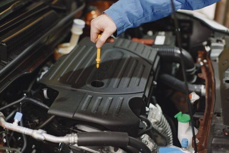 A mechanic checking transmission fluid level on a dipstick in a car engine bay