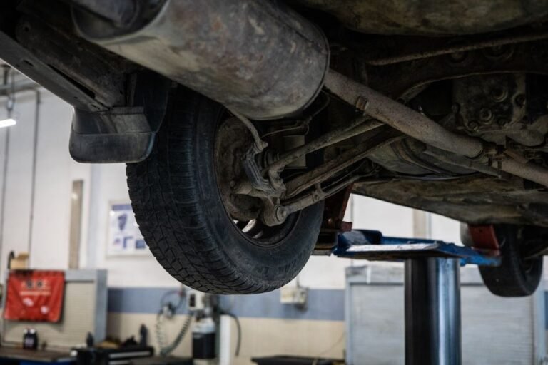 Mechanic on a shop lift inspecting a car's front suspension strut