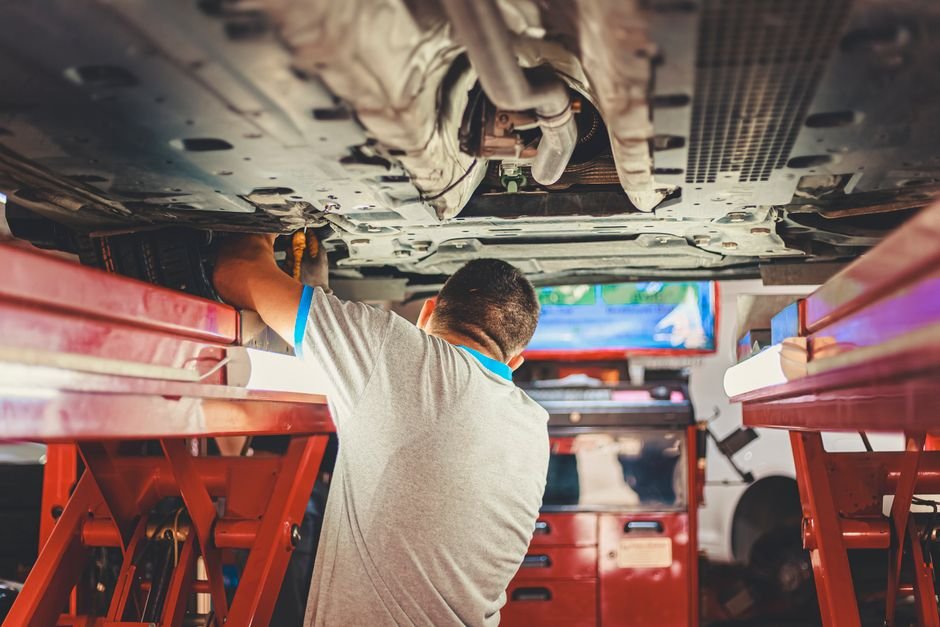 Mechanic peeling back a car's carpet to inspect the floor pan underneath for water damage