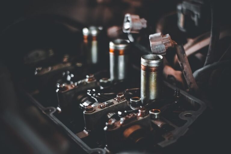 A mechanic's hand removing a spark plug from a car engine with a socket wrench