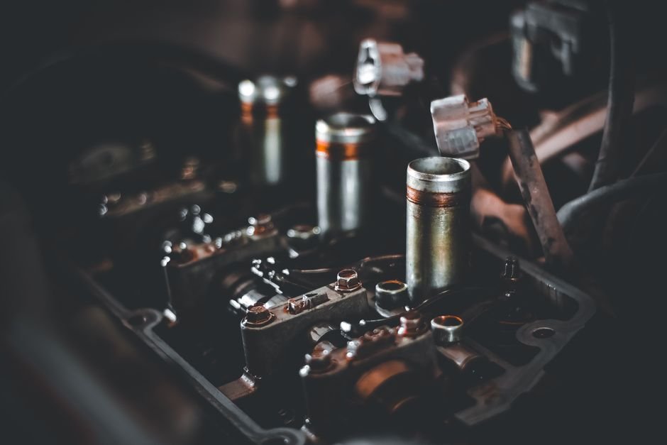 A mechanic's hand removing a spark plug from a car engine with a socket wrench