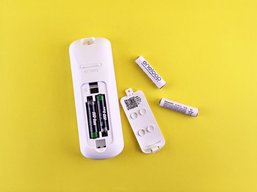 Two different brands of AA batteries loaded together in a remote control