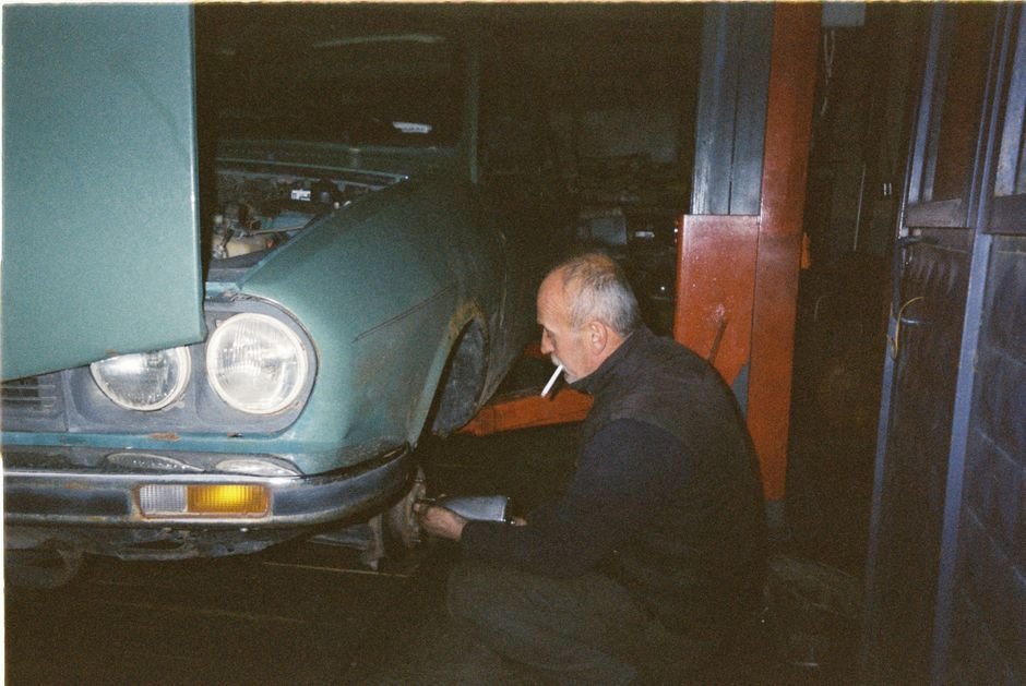 An older sedan on a lift in a mechanic's repair shop