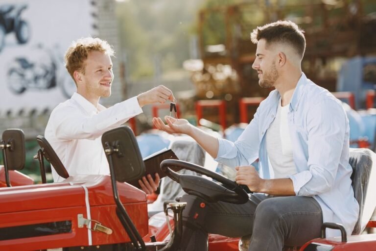 A seller handing car keys to a buyer over the hood of a parked car