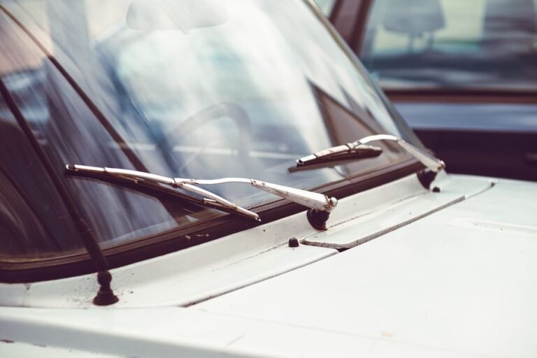 A person's hands installing a new wiper blade onto a car's windshield wiper arm