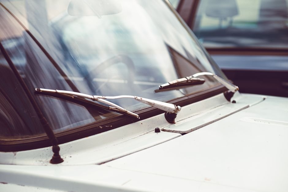 A person's hands installing a new wiper blade onto a car's windshield wiper arm