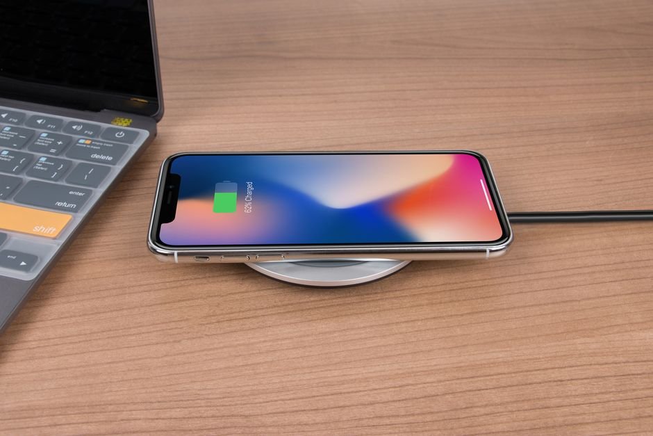A smartphone lying face up on a round wireless charging pad on a desk