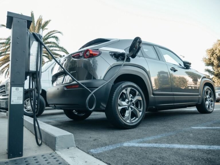 A plug-in hybrid car parked in a home driveway with a charging cable connected to its side port