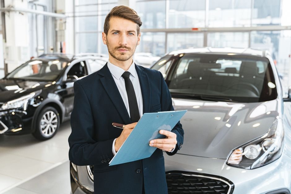 Salesperson pointing out features on a certified pre-owned car to a customer on a dealership lot
