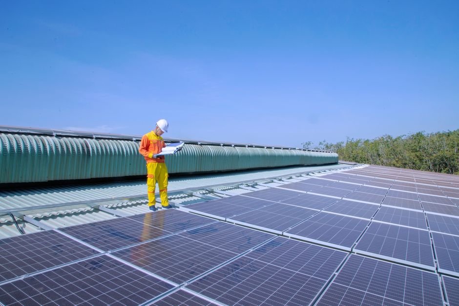 A solar installer reviewing a clipboard while standing on a residential roof