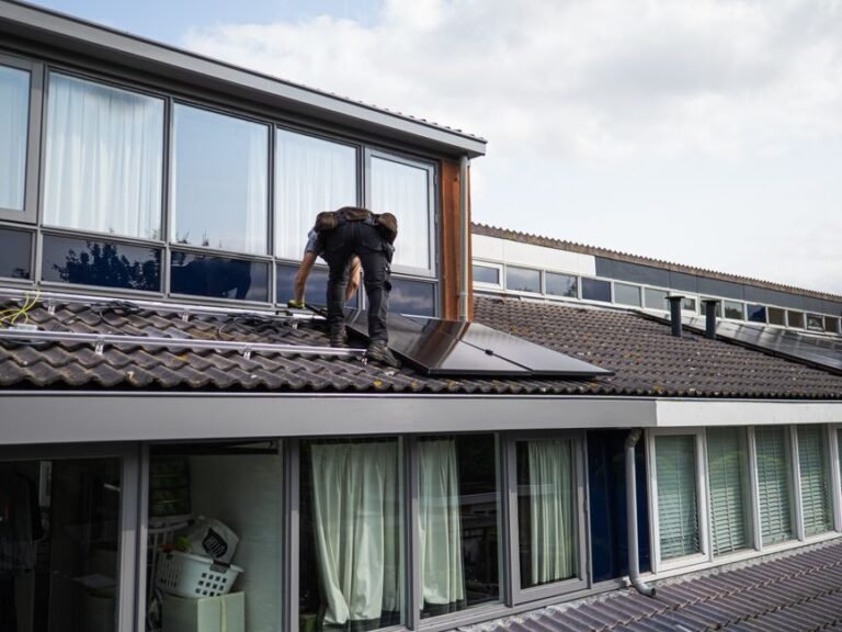 An installer securing solar panels to a residential roof frame